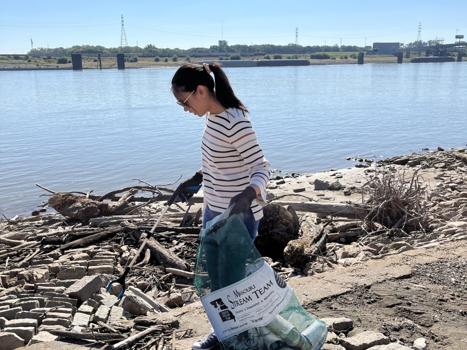 Woman picks up trash along riverfront