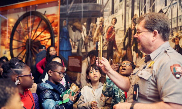 A park ranger interacts with elementary school students visiting Gateway Arch National Park as part of the Journey Fund programming. 